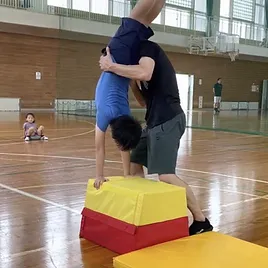 福井市教室にて、補助付き台上前転を練習する、小学校高学年の子供と、補助をする大久保先生。