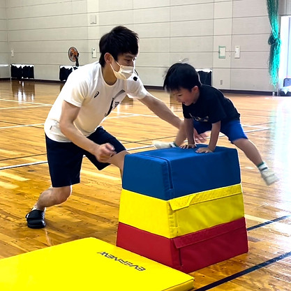 小松市教室にて、跳び箱に挑戦する幼児と、補助をする大久保先生。