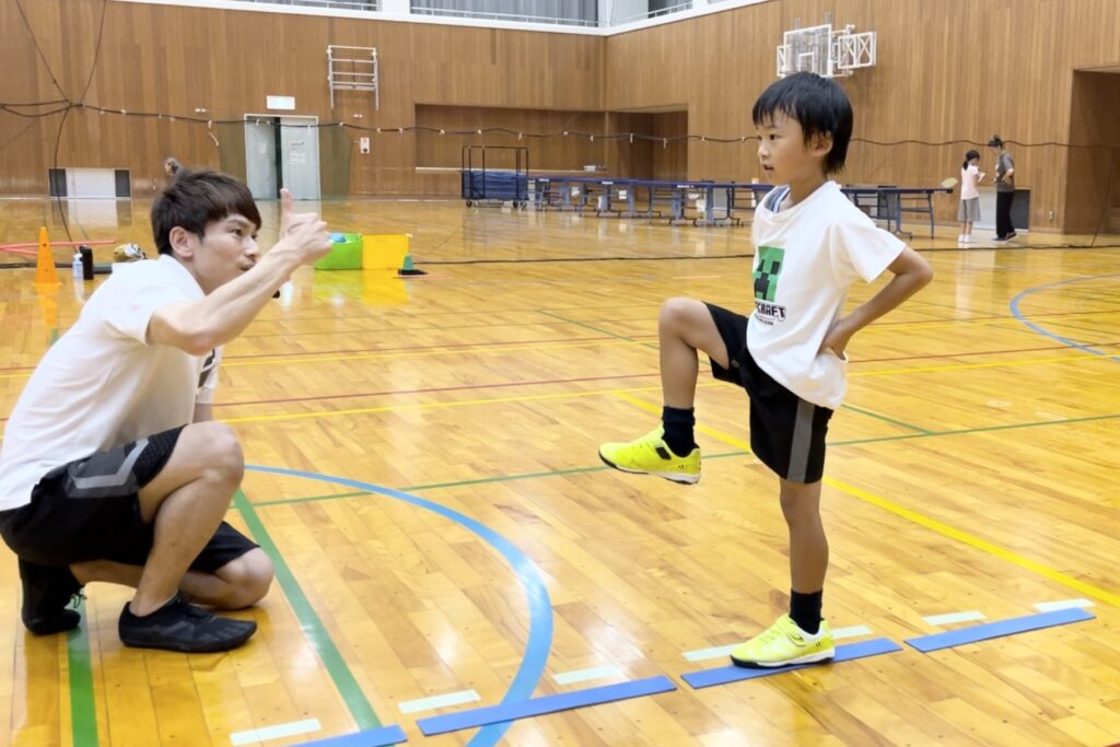 金沢市教室にて、走り方の「基本の姿勢」をつくる男の子と親指をたてグッドポーズをする大久保先生