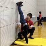小松市教室にて、補助倒立をする男児の子供と、指導する大久保先生