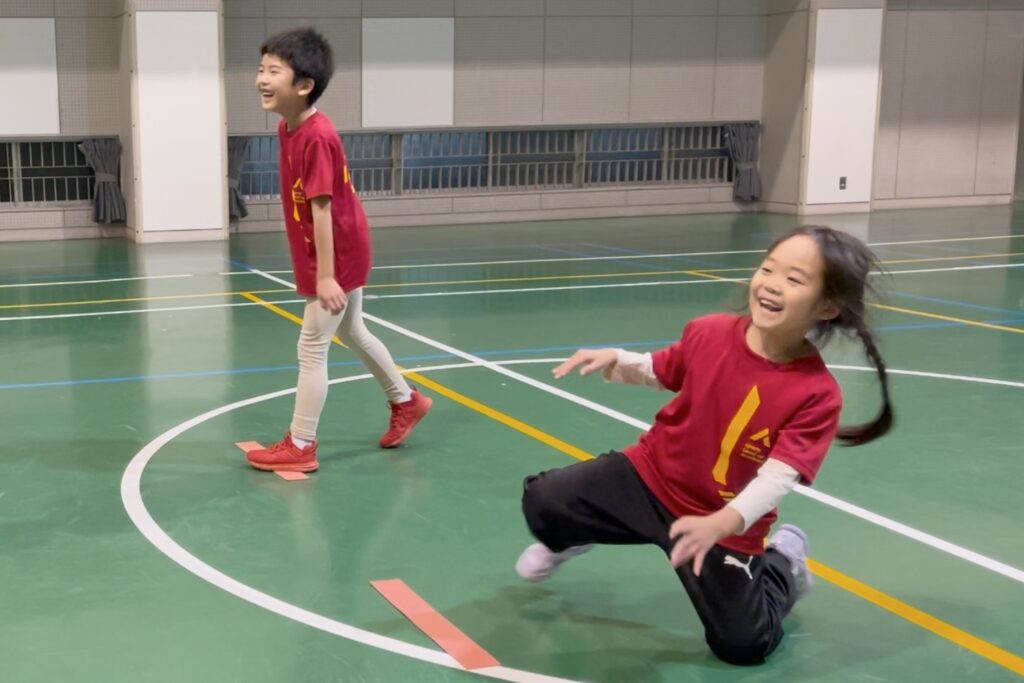 白山市教室にて、オリジナルの「反応ダッシュでスカーフキャッチ」をする、万遍の笑顔の小学生男児と女児の幼児