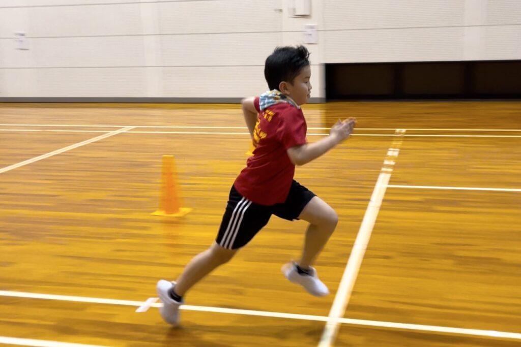 加賀市教室にて、かっこいいフォームで短距離走を走る小学生男児の子供
