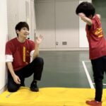 白山市教室にて、笑顔でマット運動のアドバイスをする大久保先生と、それを聞く幼児の子供