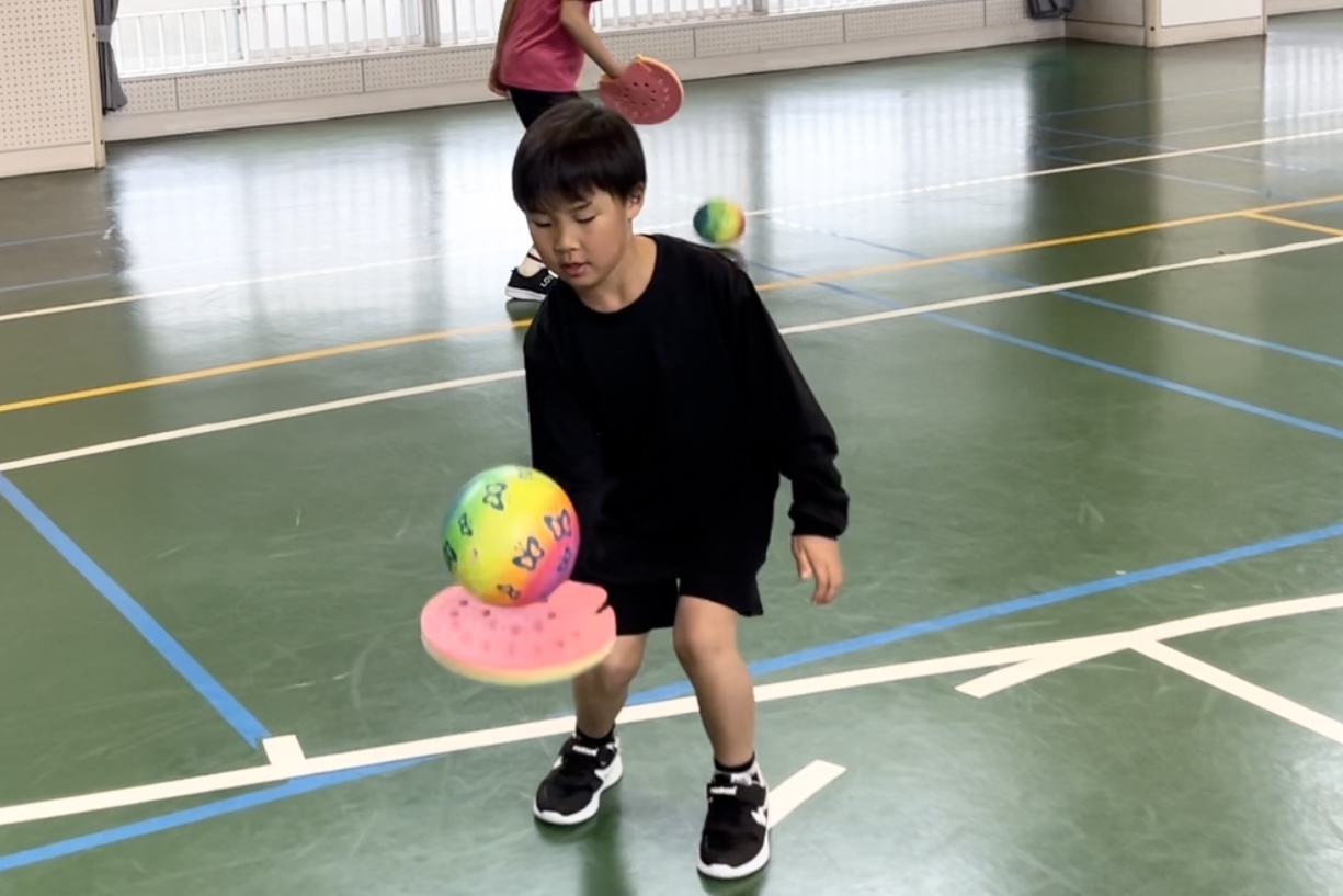 白山市教室にて、ラケットボールコントロールを練習する、真剣な表情の小学生の子供