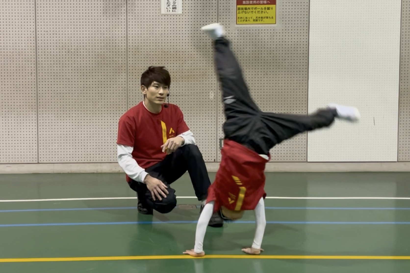 側転にチャレンジする小学校低学年の男児の子供と、それを見守る大久保先生