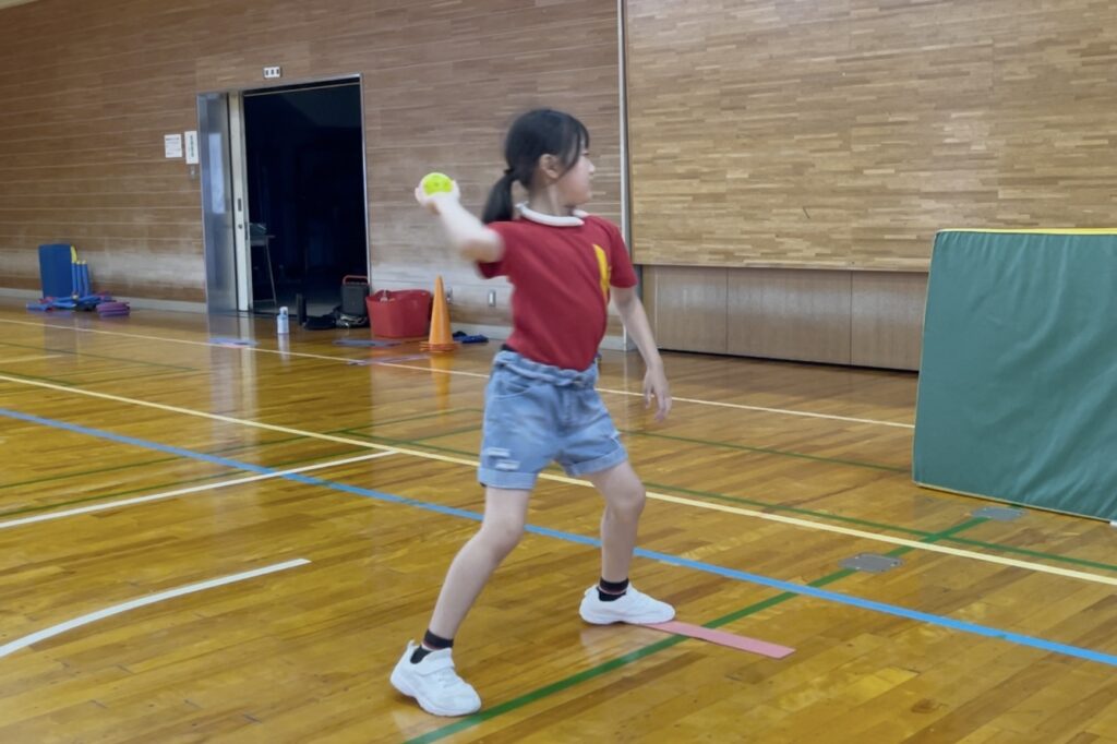 福井市教室にて、ボール投げで、「肩を引いた正しい姿勢」で投げる小学生女児の子供