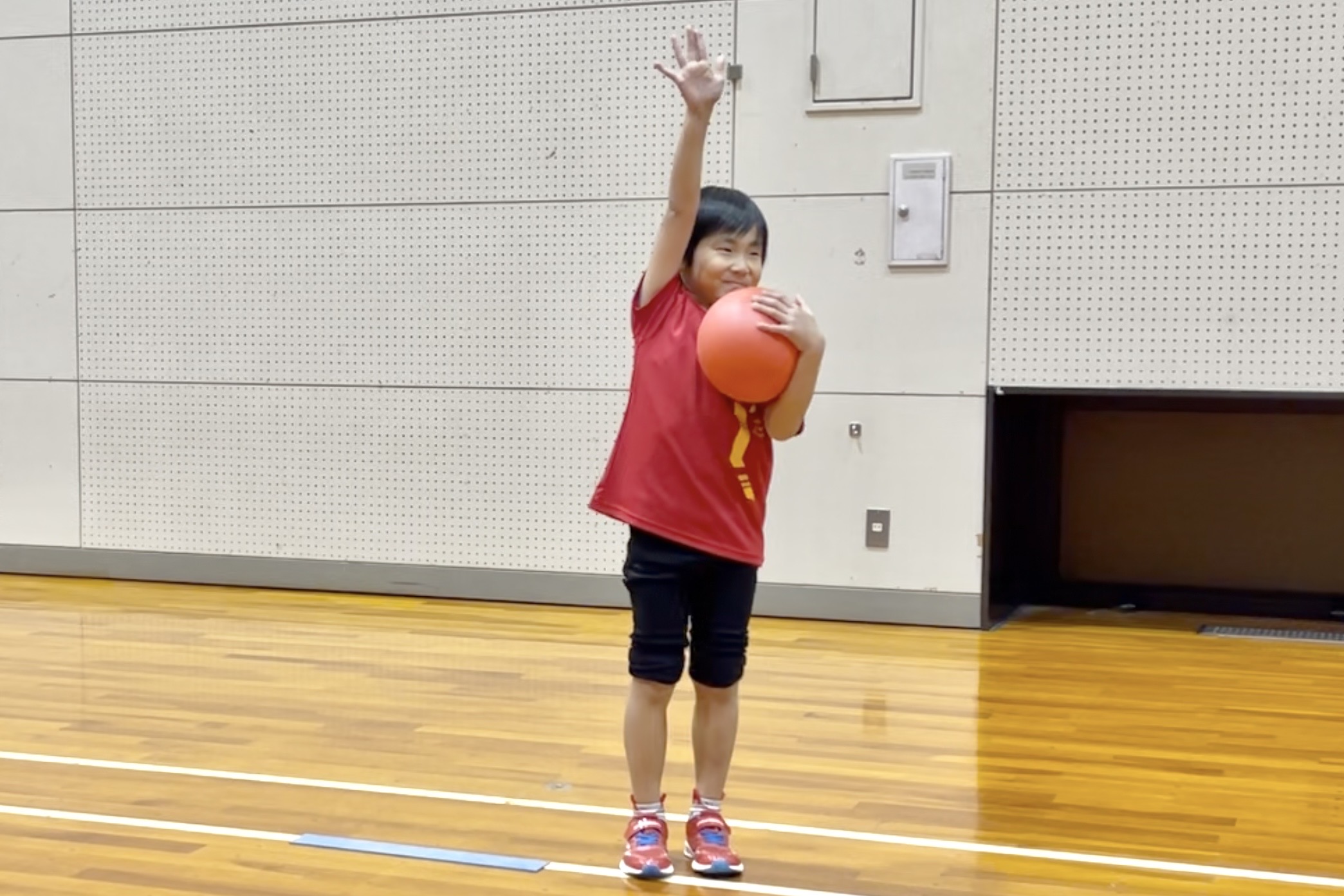 加賀市の体操教室でボール運動に取り組み笑顔で手をあげる幼児｜楽しく運動能力を育てる大久保スポーツ教室