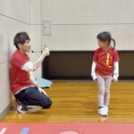 加賀市の体操教室でマット運動に成功し嬉しそうな幼児と指導する大久保先生|できた喜びを育てるスポーツ教室