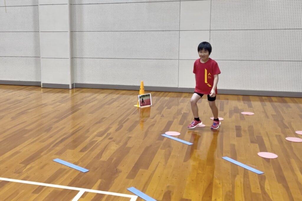 加賀市の体操教室で行う子どもの走り方練習。青線の間で感覚を意識し、そのままスピードを出す練習方法。