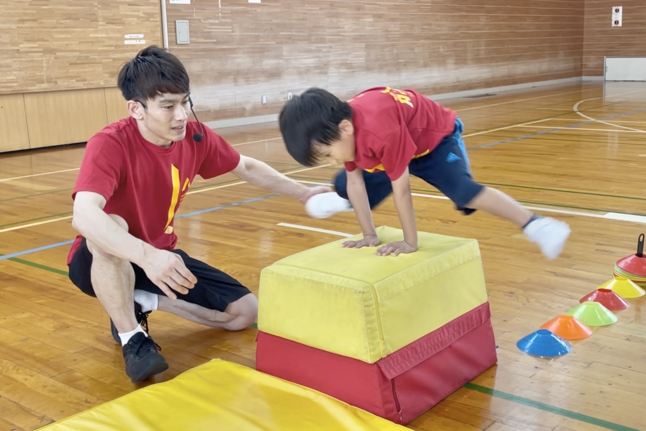 福井市の子供向け体操教室で、幼児が跳び箱から離れた位置からジャンプして跳び箱を跳ぶ基礎練習に挑戦している様子