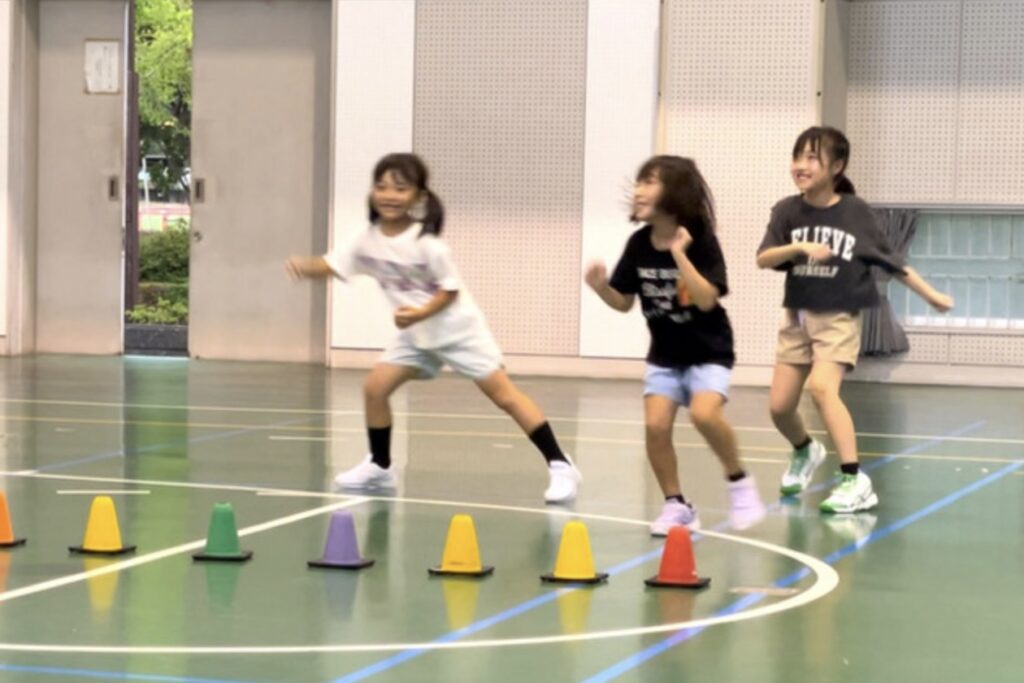 白山市の体操教室で、オリジナルの壁おにごっこを笑顔で楽しむ3人の女の子