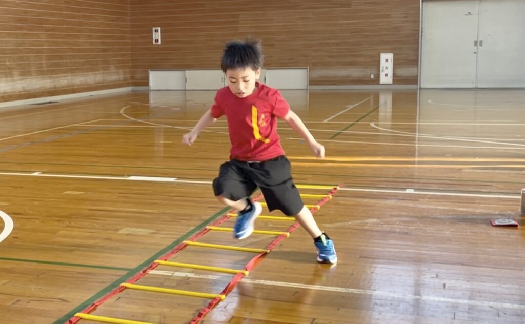 福井市北体育館にて、ラダートレーニングを真剣な表情で行う、かっこいいフォームの幼児