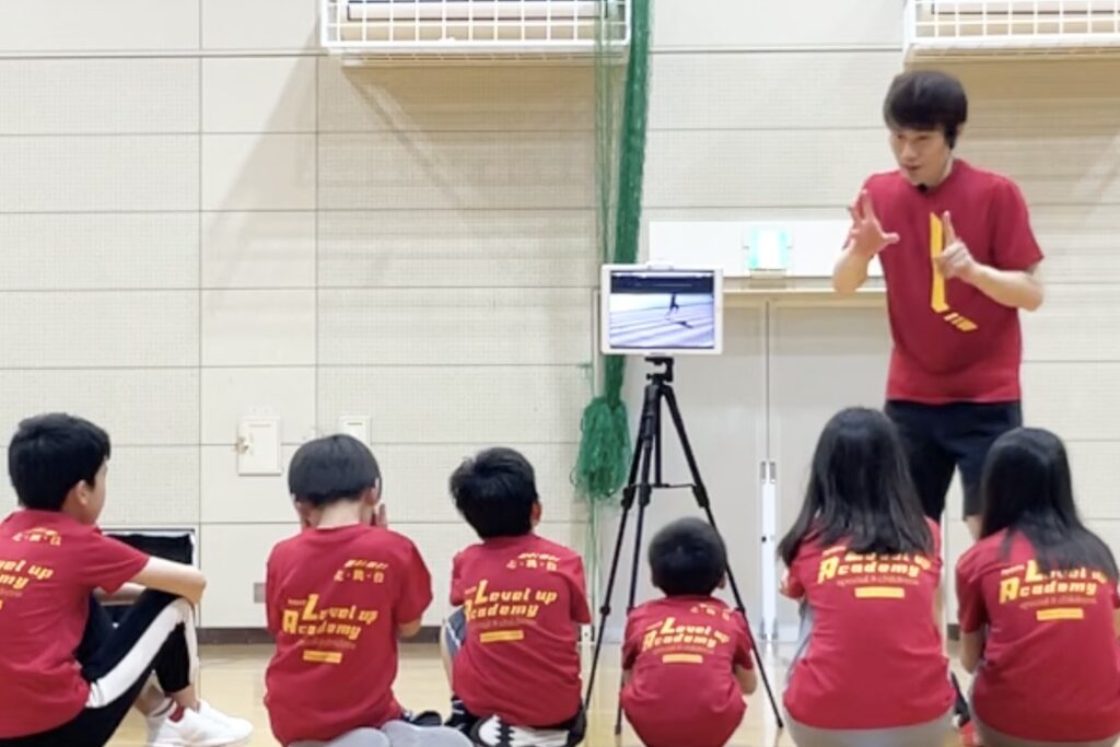 小松市教室にて、ダブレットを併用する独自の指導方法で、子供たちに動きのポイントを教える大久保先生と、その説明を聞く子供達