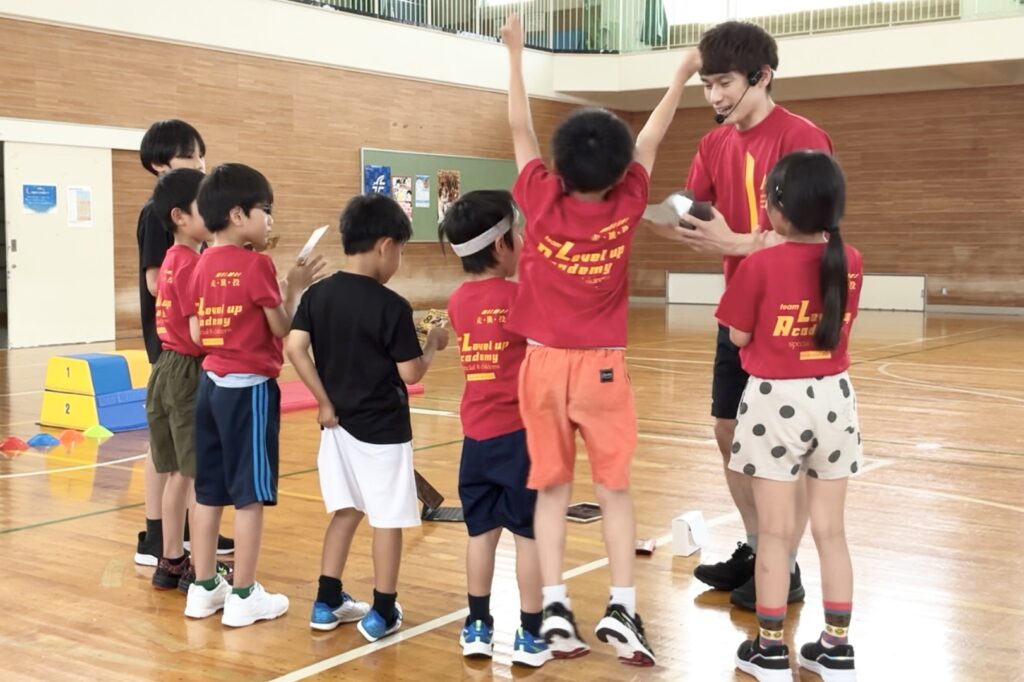 福井市教室参加の子どもたちに、独自の技術認定書である「称号カード」を渡す大久保先生と、それを受け取る子どもたち