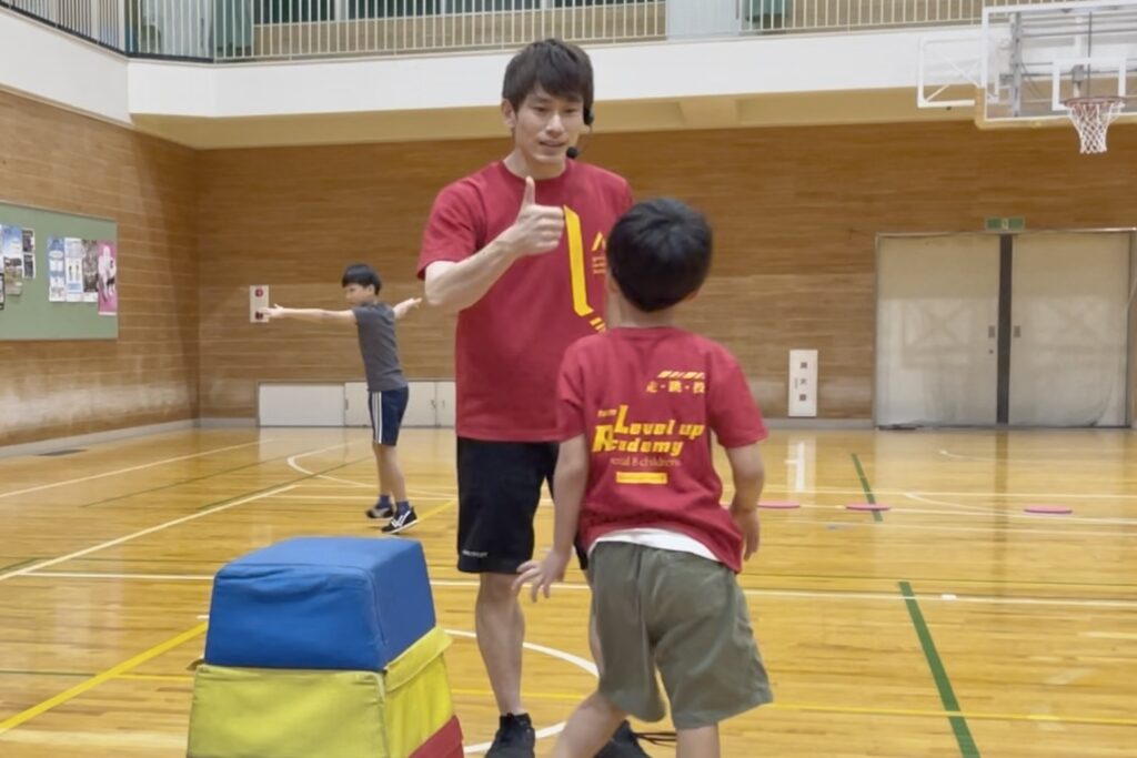 福井市教室にて、跳び箱が跳べた子供に、笑顔でグッドマークをする大久保先生