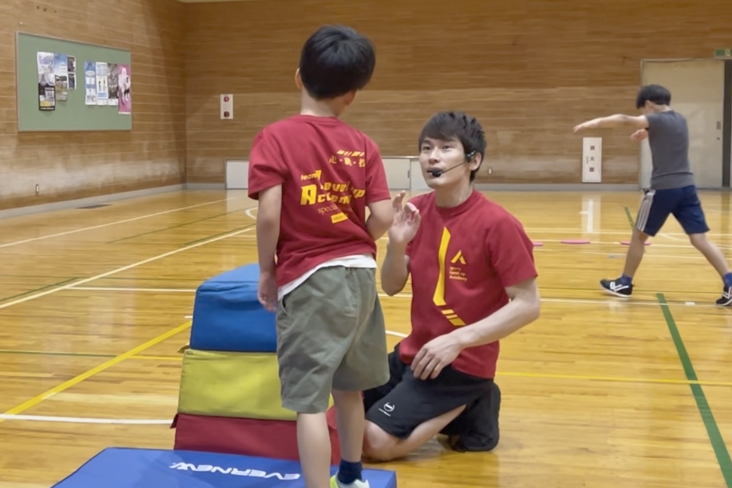 福井市教室にて、跳び箱のアドバイスをする大久保先生と、その説明を聞く幼児の子供。